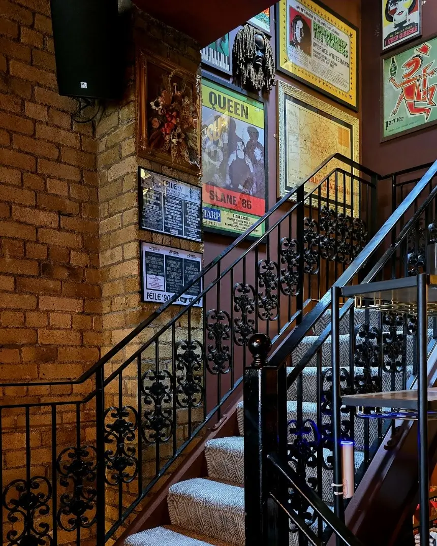 Victorian era staircase with ornate wrought iron railings and vintage poster collection at Fitzers Bistro & Bar Dublin
