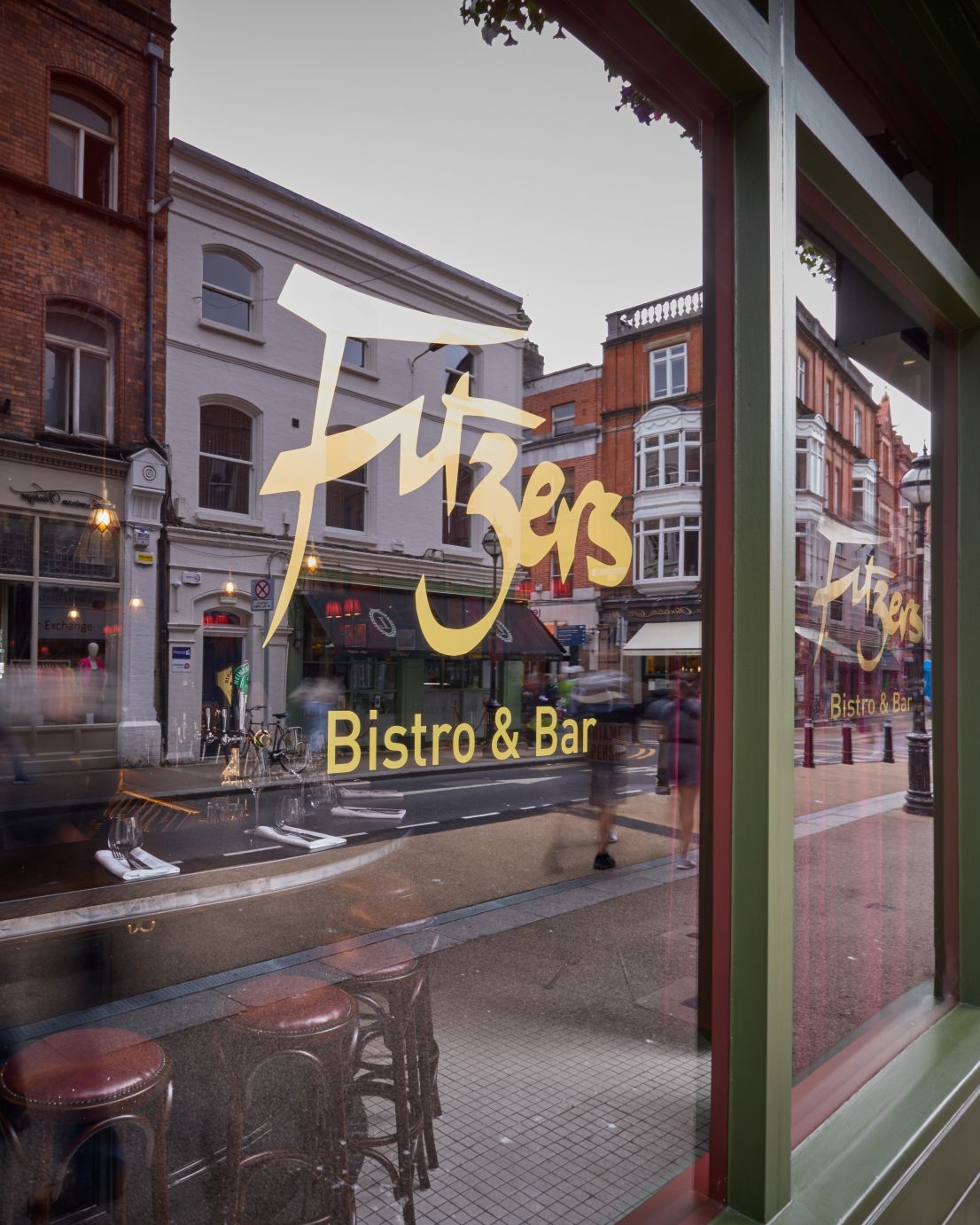 The gold 'Fitzers Bistro & Bar' logo on the front window, with a view looking out onto the bustling Exchequer Street in Dublin.